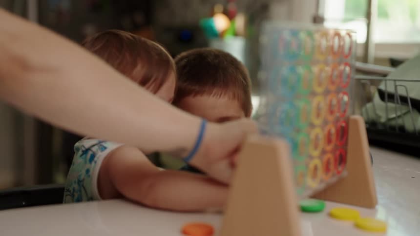 Children play connect four with their mother