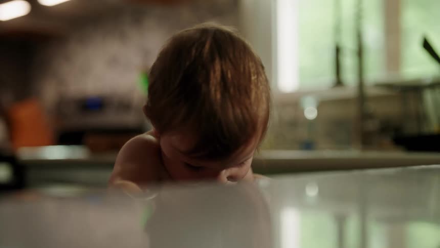 Shirtless baby having fun in the kitchen