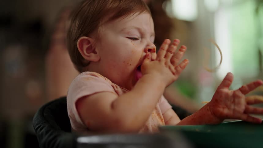 Baby getting his hands dirty with pasta in red sauce