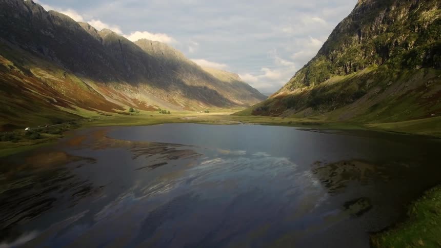 A large mountain area with some water in a pond next to it