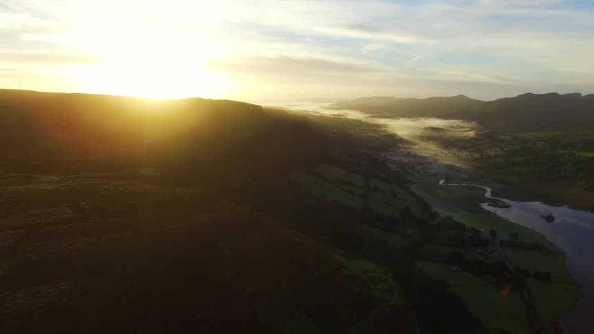 Sunshine peaks over the top of a cliff on the shoreline