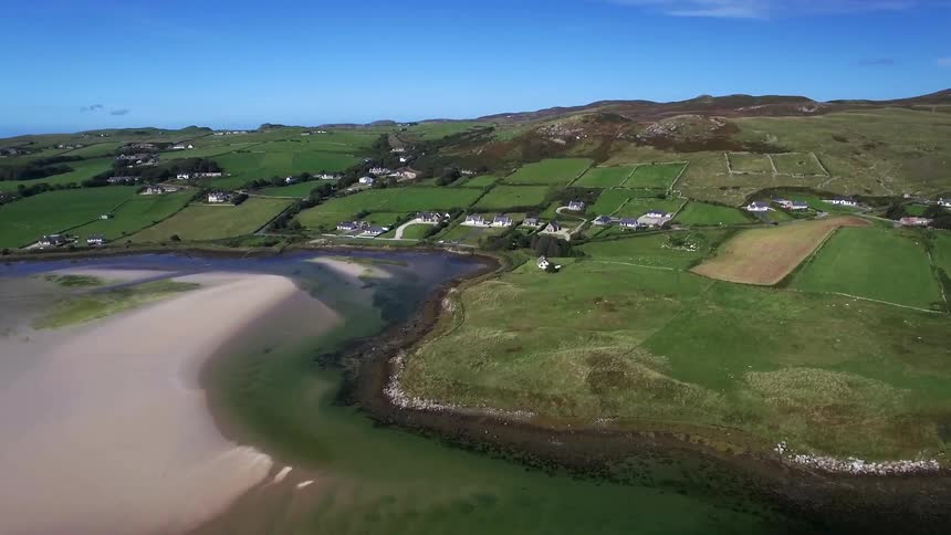 An aerial view of a ocean next to a hilly piece of land