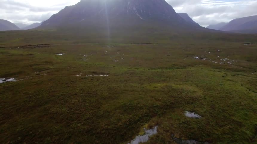 Below is a long green pasture leading to a mountain