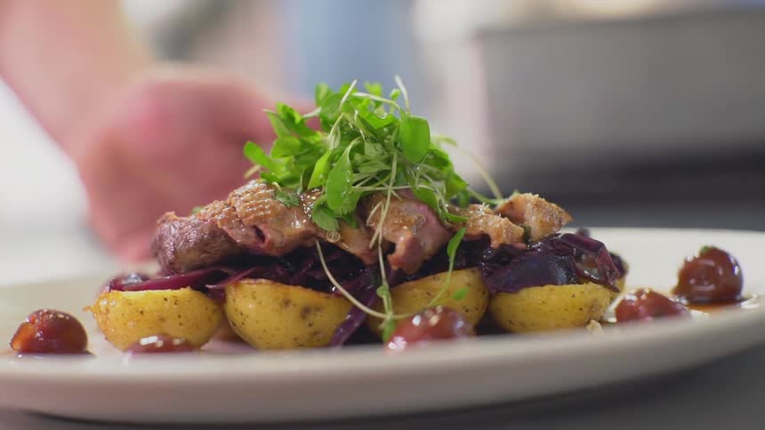 A chef pushes a plate of food forward