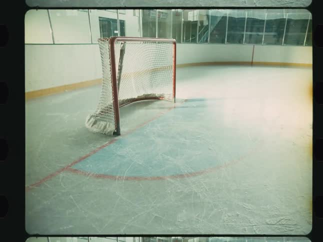 Bright light shines and illuminates an ice hockey field with its goalposts standing still on the ice