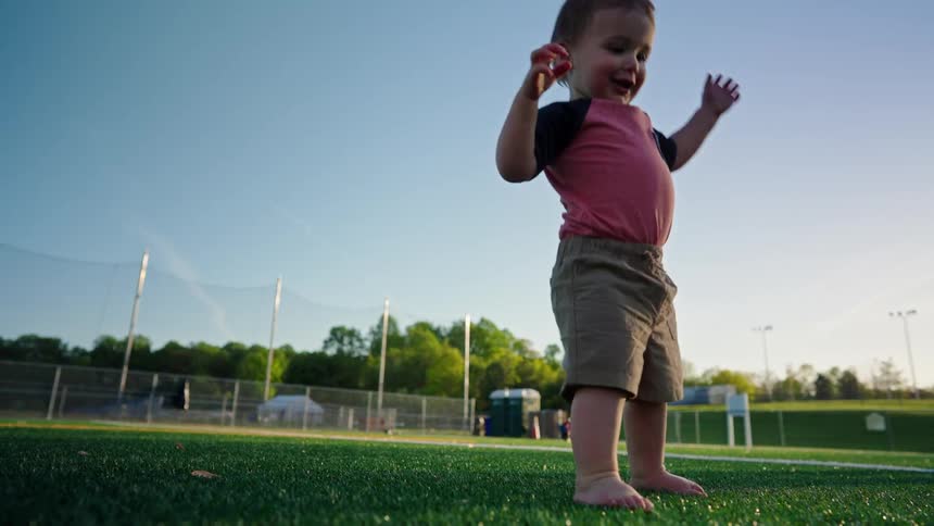 Boy on a synthetic grass field holding and releasing a soccer ball