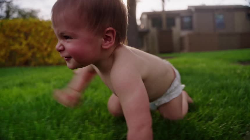 Smiling baby crawling on green grass