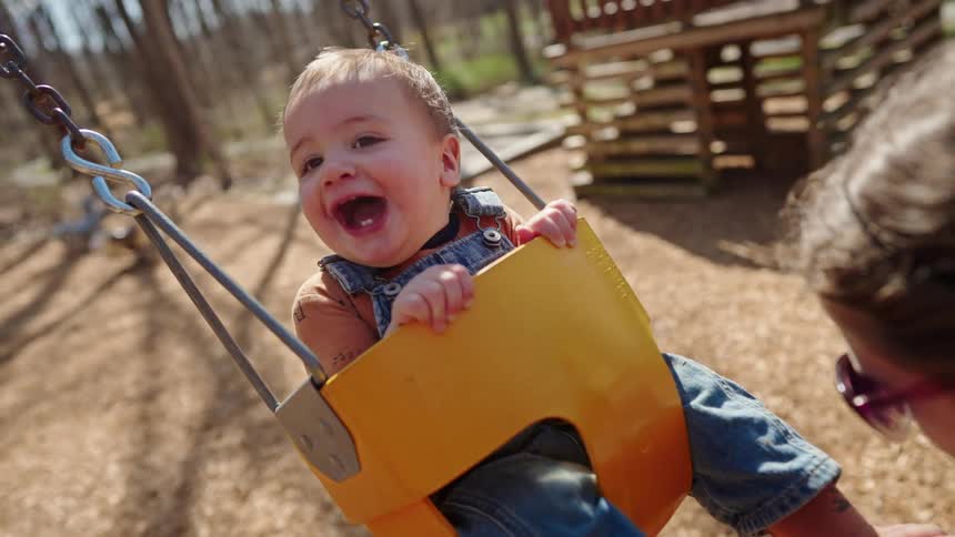 Little boy having fun on a swing at a playground during the day