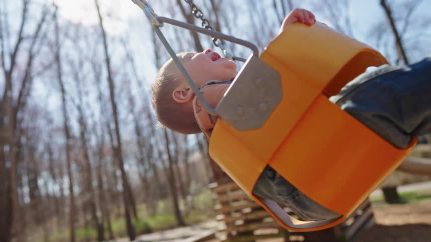 Mother playing with a baby who is having fun on a swing outdoors