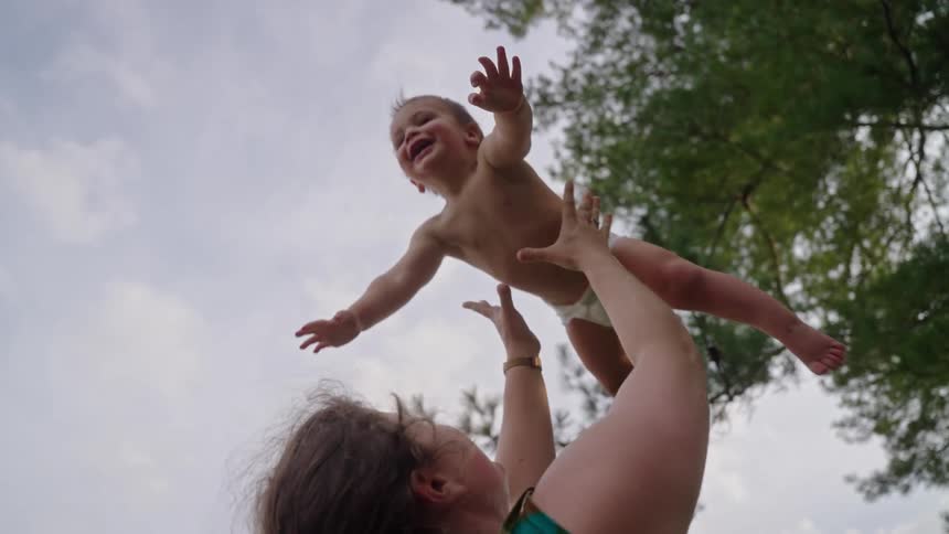 Woman holding a smiling baby outdoors