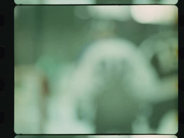 A blurry outoffocus hockey team moves against a hazy green and white background all contained within a black filmstrip border
