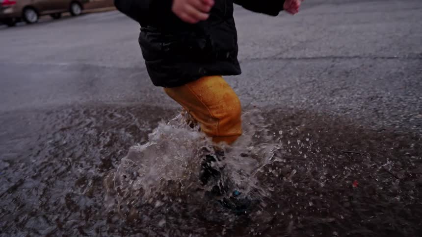 Little boy having fun splashing in a puddle on the street