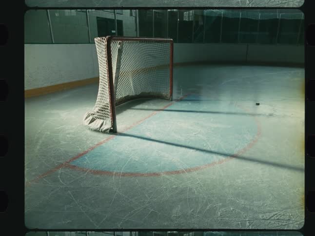 A filmstripstyle video opens up to an empty hockey rink where a hockey goal is seen as pucks hit it