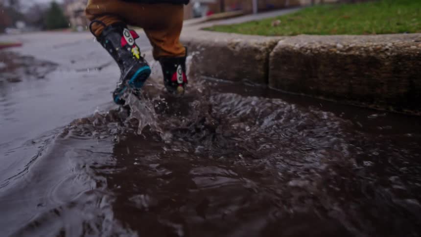 Child in boots walking in a puddle