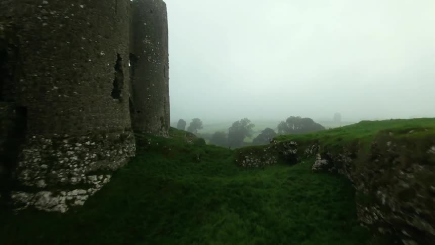 A run down building on top of a large hill that is green
