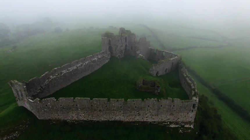 A long stone wall lines a green hill on a foggy day