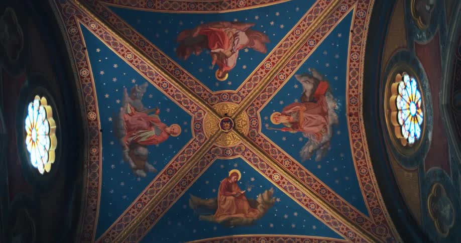 A slow pan across a domed ceiling shows an intricate design of dark blue and gold patterns with four different painted scenes of religious figures in the center and stained glass windows on either side
