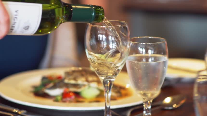 A person pours wine into a glass