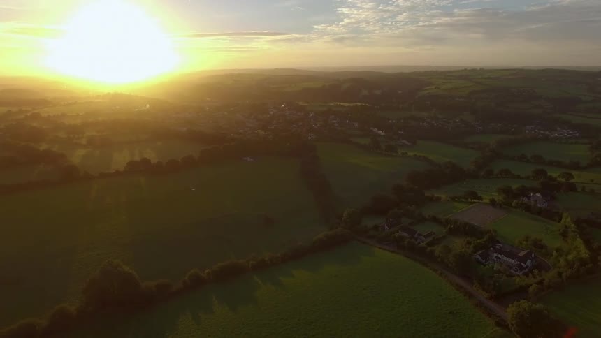 The sun is rising in the distance over this field