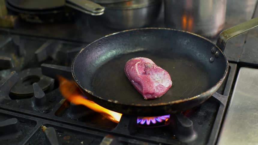 A steak is cooking in a skillet