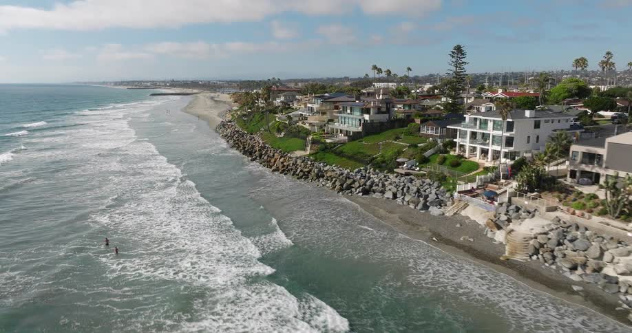 A rugged coastline captured from an aerial perspective with a lot of houses and a cloudy sky