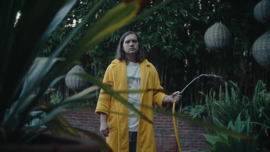 The gardener is spraying the hose in the garden