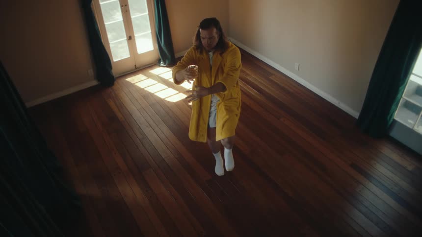 Man holding an alcoholic beverage balances while moving in an empty room