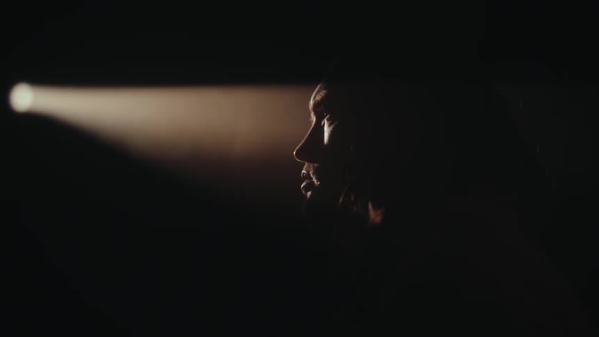 A person side profile lit by narrow beam in darkness