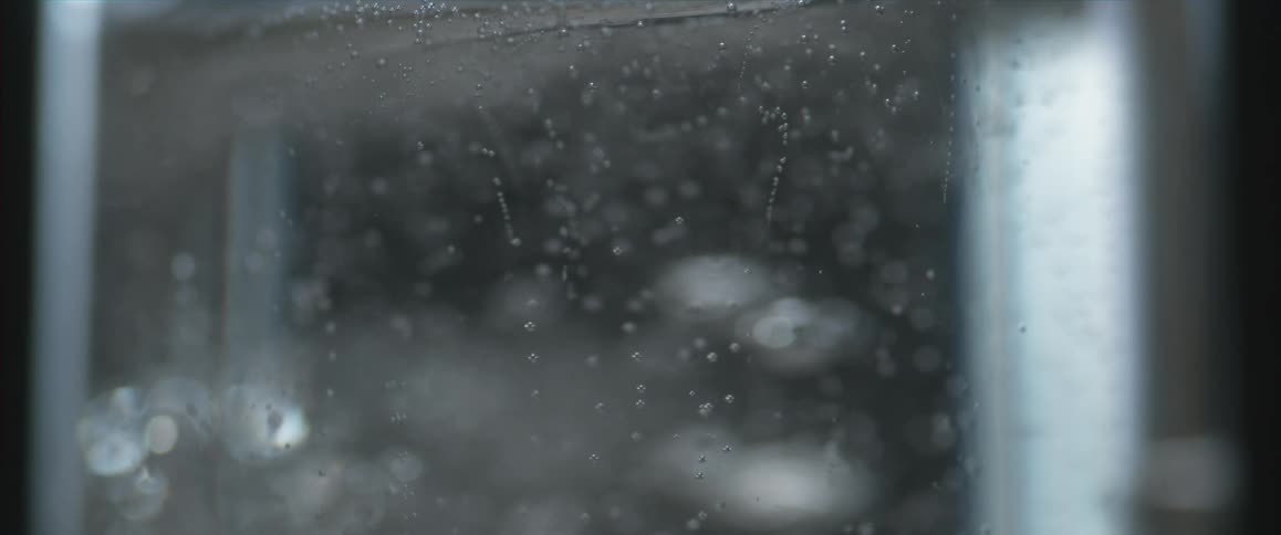 Tight shot of a bubbly liquid pouring into a container and filling it up