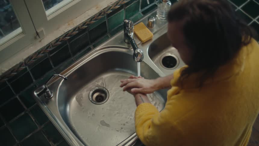 A person is washing hands in a kitchen sink
