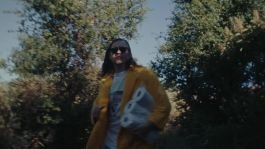 Man in sunglasses running outdoors holding a pack of toilet paper