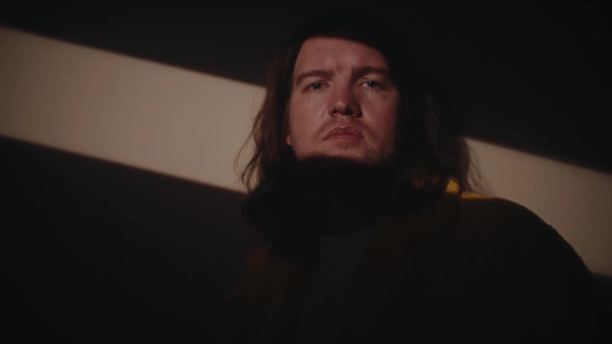 A person with long hair staring directly at the camera with a serious expression