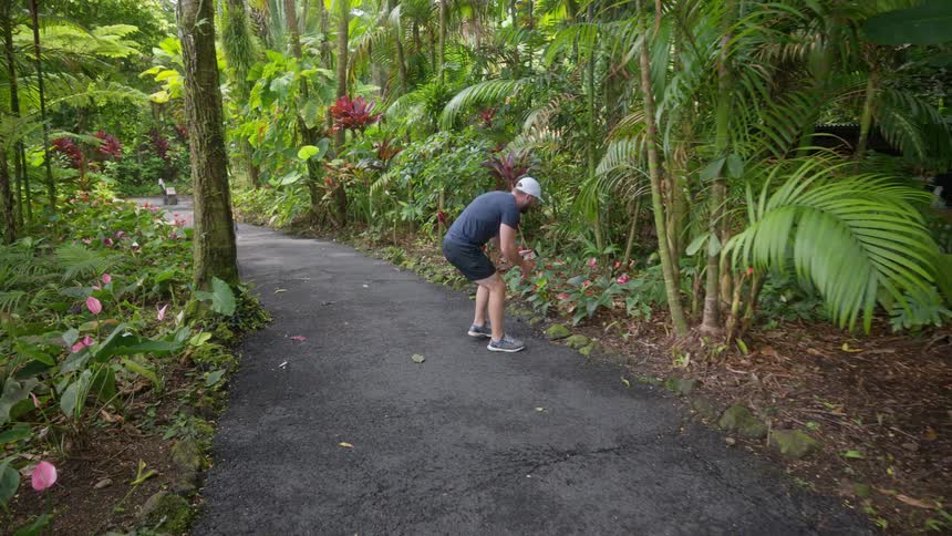 Man photographing flowers in a wooded trail environment in a park