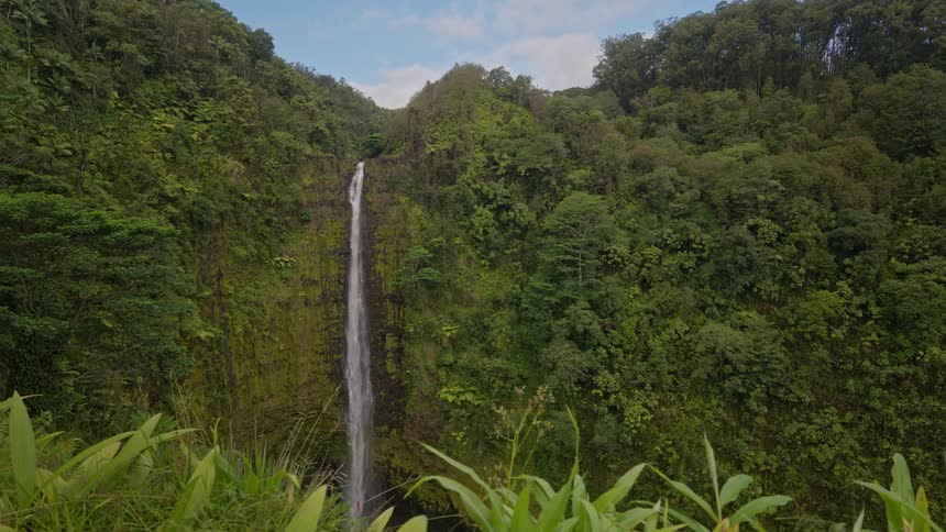 A large waterfall cascades down a cliff covered in lush greenery