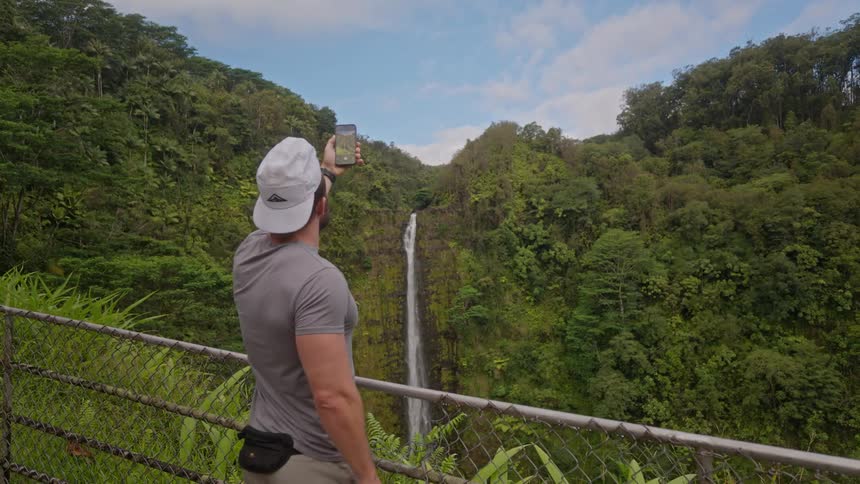 The man is taking pictures of a waterfall