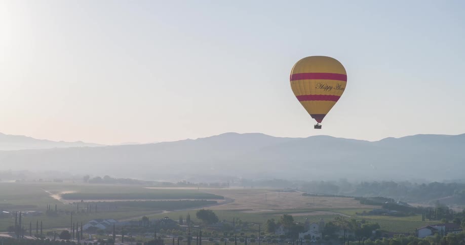 Yellow balloon flying over a natural area with mountains in the background