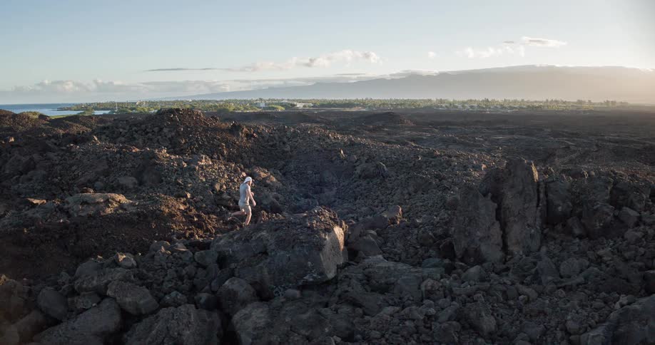 Man walking among rocks and stones in a natural environment with the sea in the background