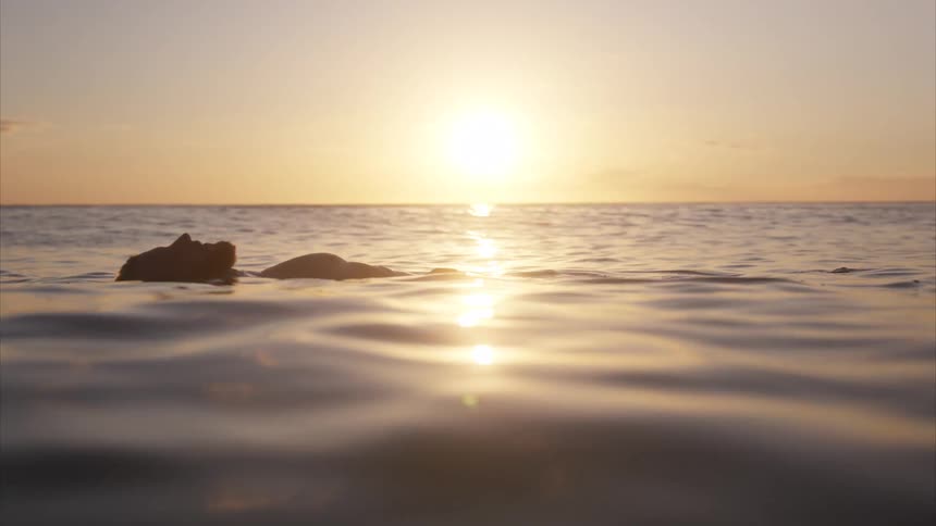 The man is floating on his back in the ocean