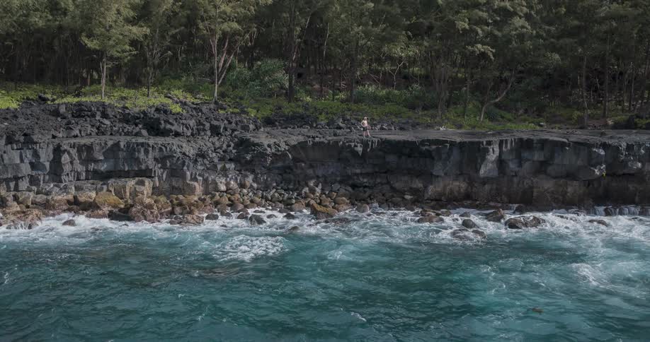 A man is standing on the cliff of the shore