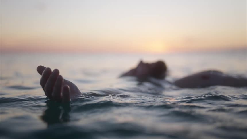 A man floats on his back in an ocean with gentle waves