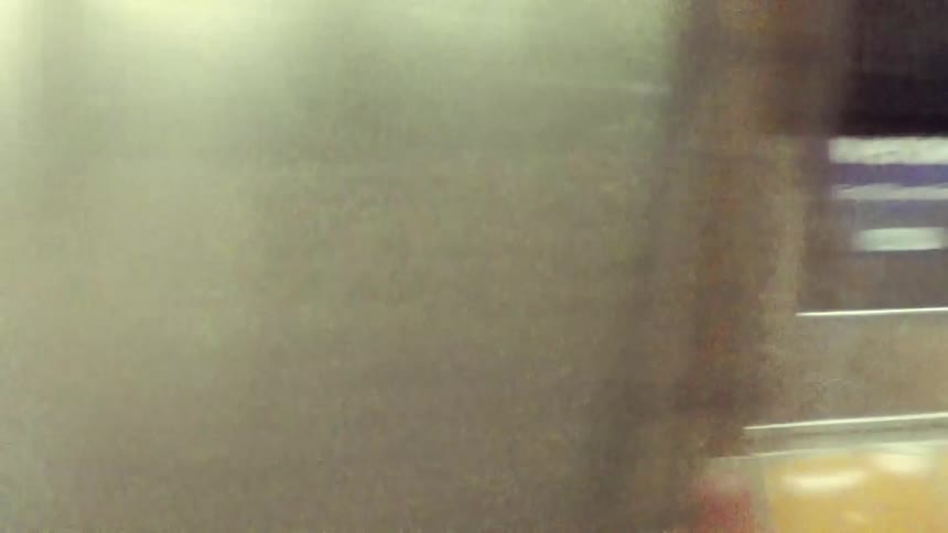 A woman walks past the moving subway train