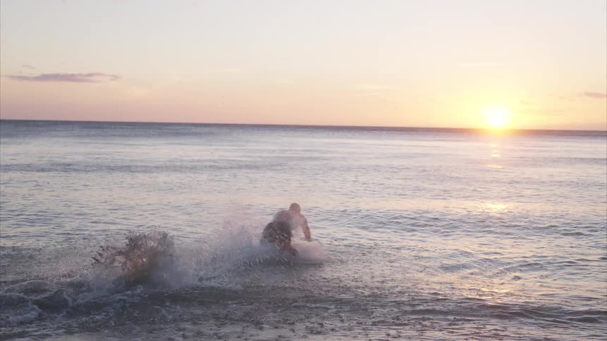 A man runs on the beach and dives in the water