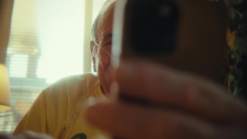 An elderly man using his smartphone and laughing happily