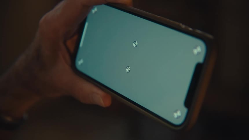 Man holds his phone with a green screen and circles in the corners