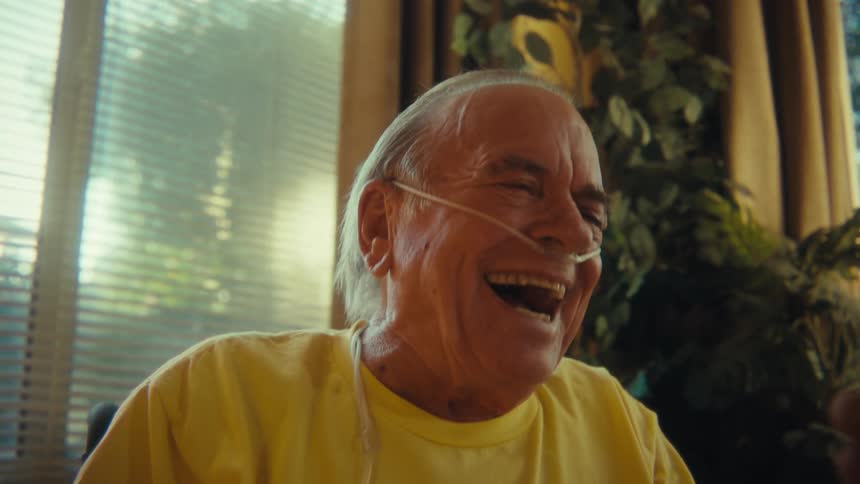 Elderly man sitting laughing interacting with smartphone