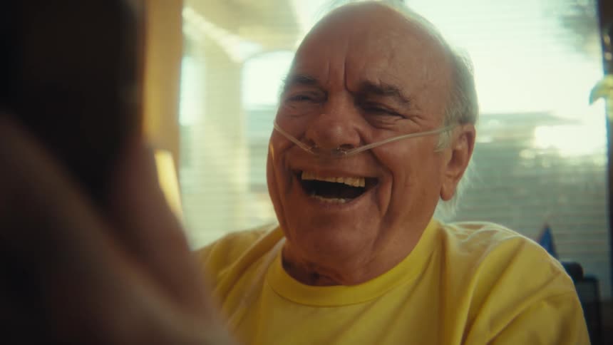 Elderly man in a yellow army veteran shirt using a cellphone