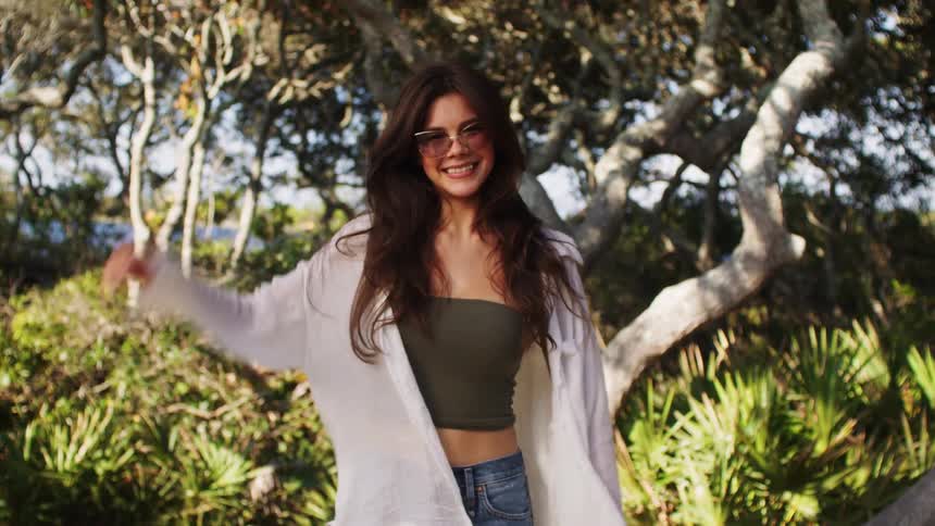 A smiling young woman poses in different ways in front of a tree