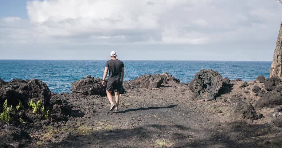 Man walking on rocky terrain towards the sea