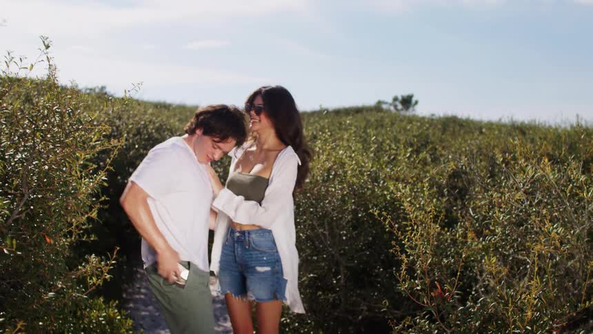 Man and a woman taking a selfie in a field with green vegetation