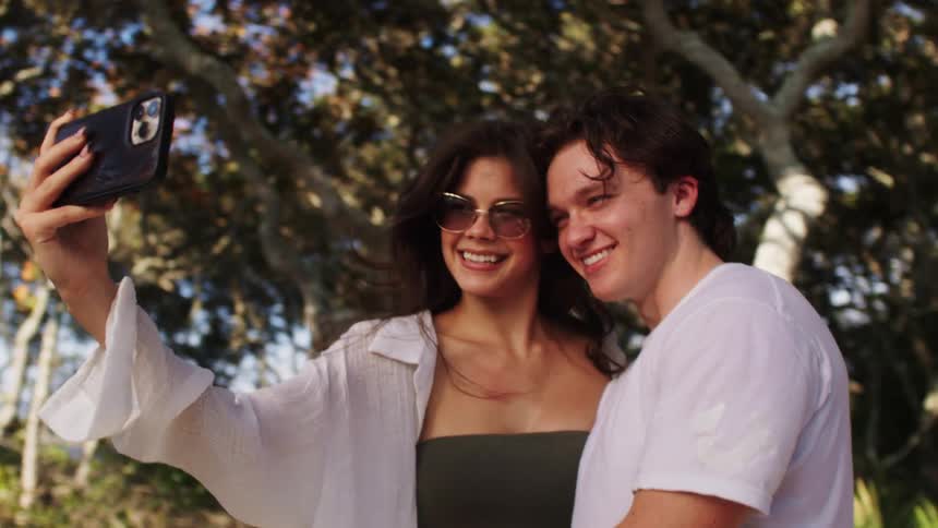 Couple outdoors in a setting surrounded by trees taking a selfie